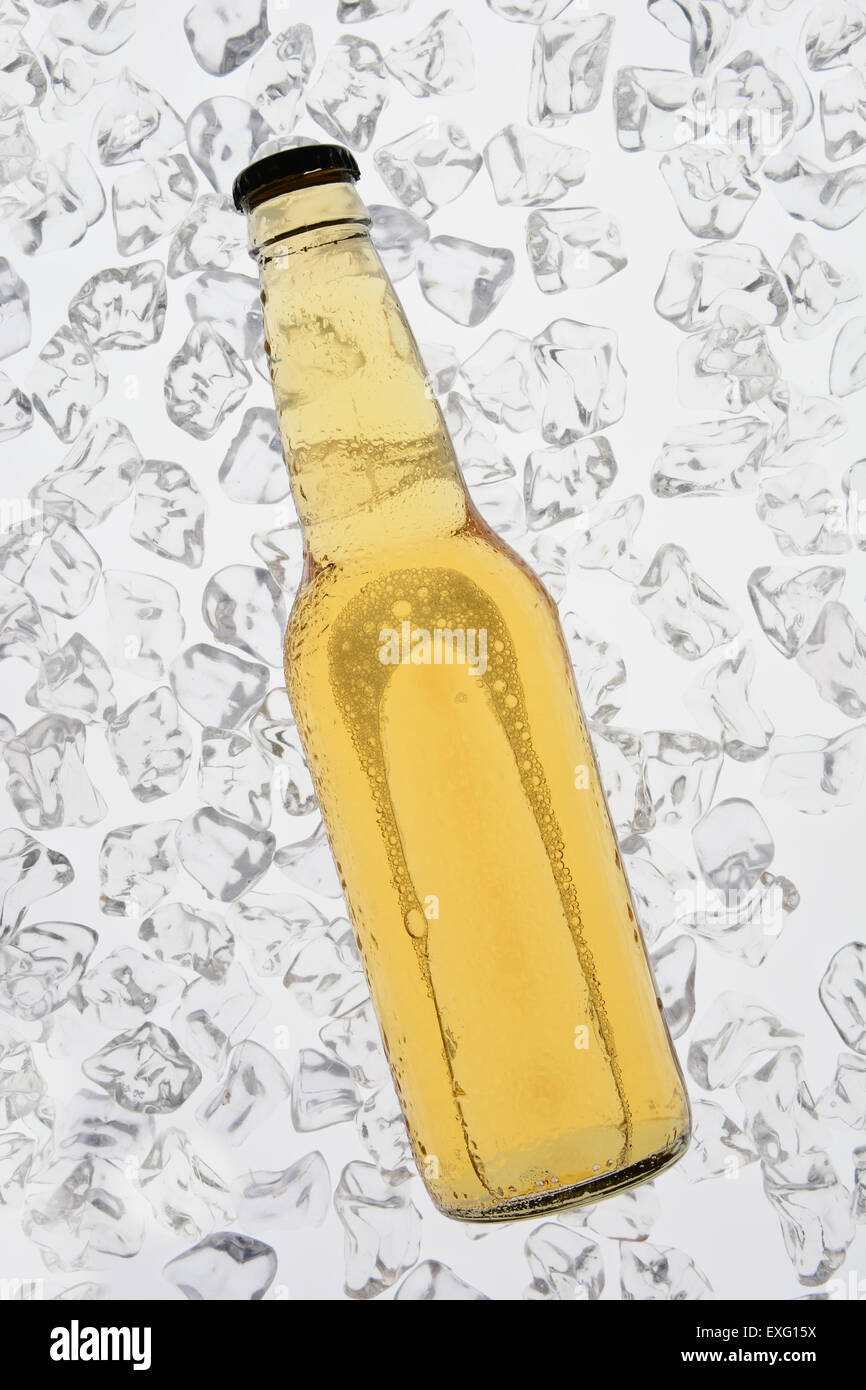 Una sola bottiglia di birra backlit su un letto di ghiaccio. La bottiglia non ha alcuna etichetta. Formato verticale Foto Stock