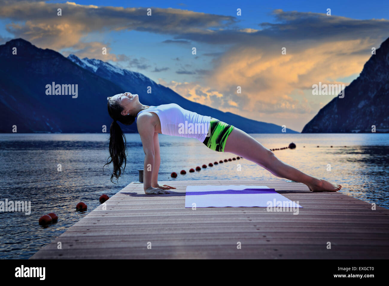 Donna fare esercizi yoga presso un lago Foto Stock