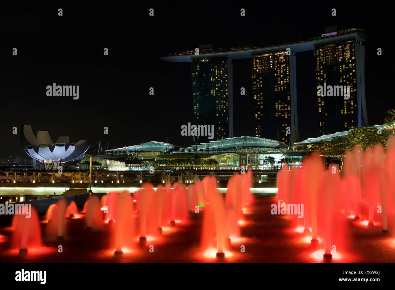 Colore rosso fontane al di fuori del Fullerton Bay Hotel, il Marina Bay Sands Hotel in background, Singapore. Foto Stock