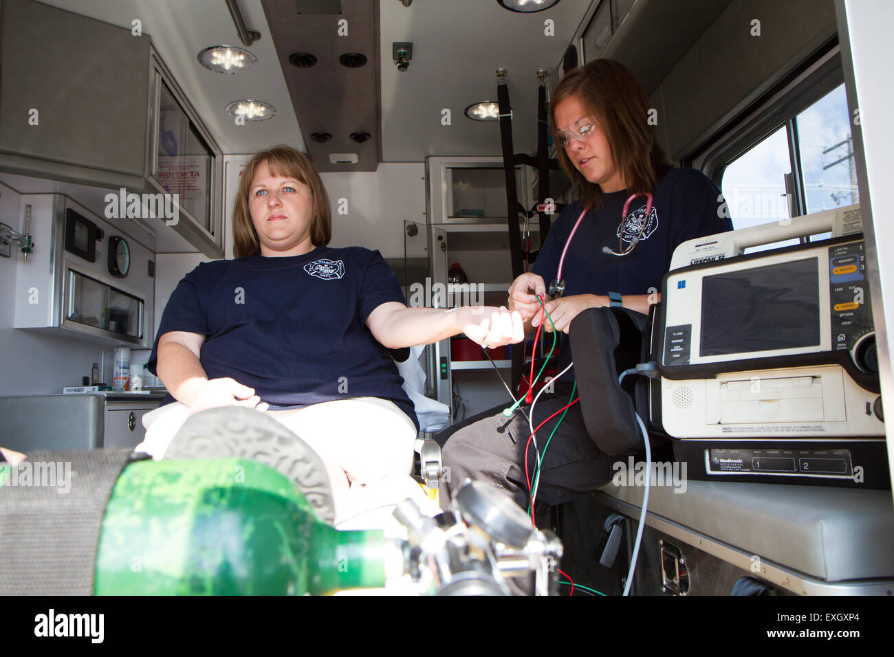 I paramedici femmina lavora nel retro di un'ambulanza. Rurale noi volontari dei vigili del fuoco. Foto Stock