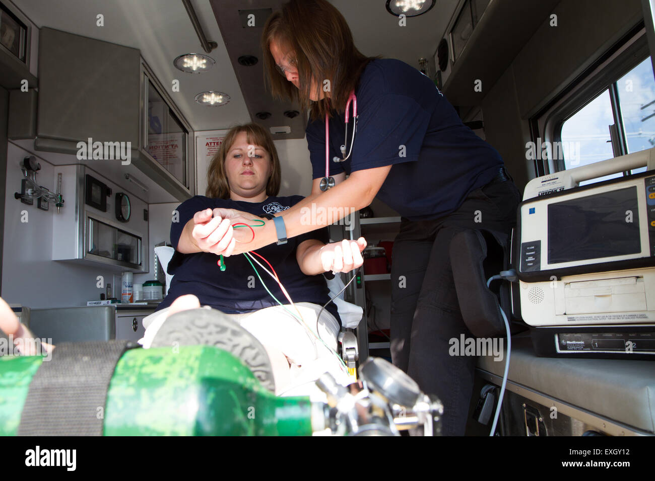 I paramedici femmina lavora nel retro di un'ambulanza. Rurale noi volontari dei vigili del fuoco. Foto Stock