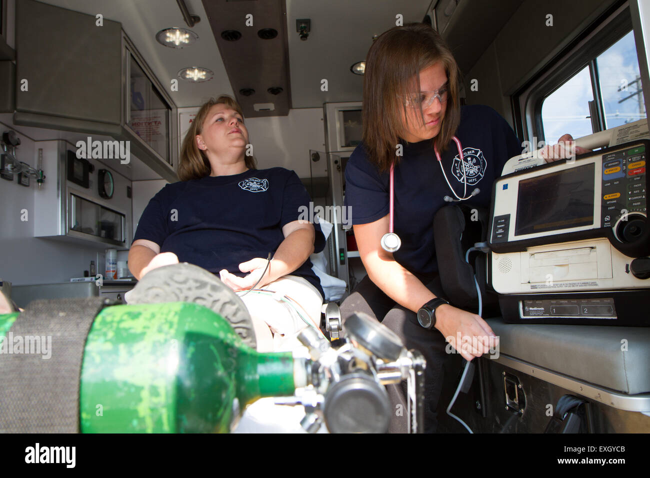 I paramedici femmina lavora nel retro di un'ambulanza. Rurale noi volontari dei vigili del fuoco. Foto Stock