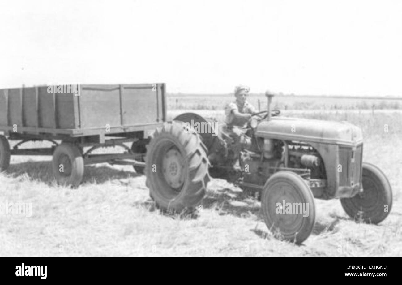 Questa foto cattura Melvin Roth con bambini della comunità mennonita di Milford, Nebraska. Probabilmente la scena mette in risalto la vita quotidiana in una comunità rurale mennonita, con un'attenzione particolare all'agricoltura, simboleggiata dai trattori e dai campi di grano. Foto Stock