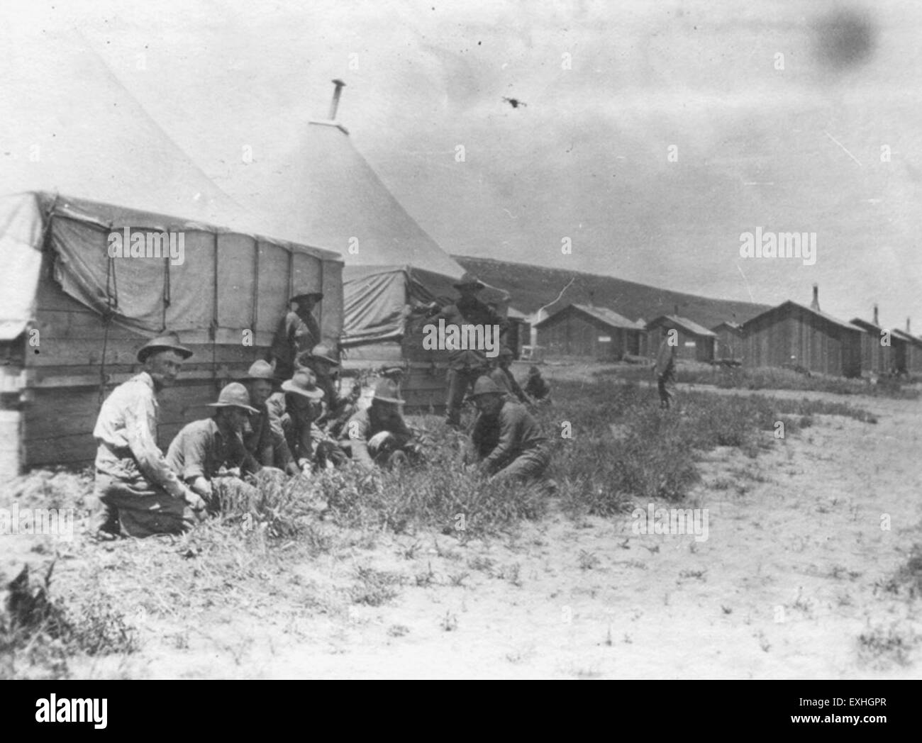 Una fotografia raffigurante uomini seduti davanti a una tenda nel campo di detenzione 12, che cattura un momento nella storia del campo durante la sua operazione. L'immagine evidenzia le condizioni del tempo. Foto Stock