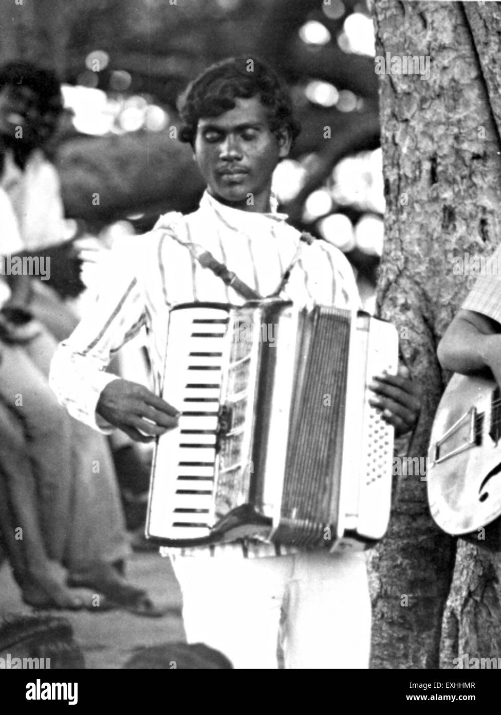 La fotografia di M. D. Jacob, fisarmonicista di Mahbubnagar, India, scattata nel 1973, mostra il suo talento musicale e il patrimonio culturale della regione. L'immagine cattura un momento di esibizione, riflettendo la tradizione musicale locale. Foto Stock