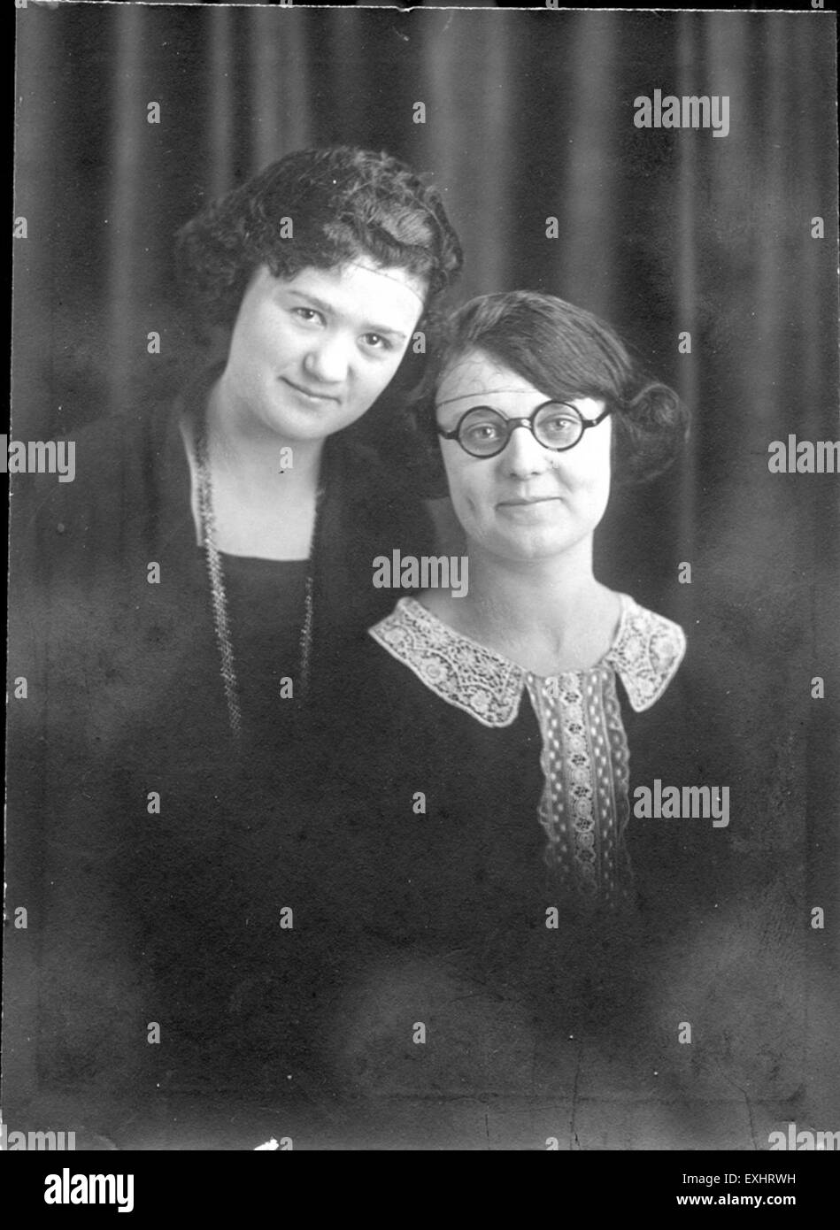 Questa fotografia in bianco e nero degli anni '1920 presenta due donne non identificate che catturano la moda e lo stile sociale dell'epoca. L'immagine fornisce uno sguardo sull'abbigliamento, le acconciature e l'estetica generale delle donne all'inizio del XX secolo, riflettendo le norme e le tendenze sociali del tempo. Foto Stock