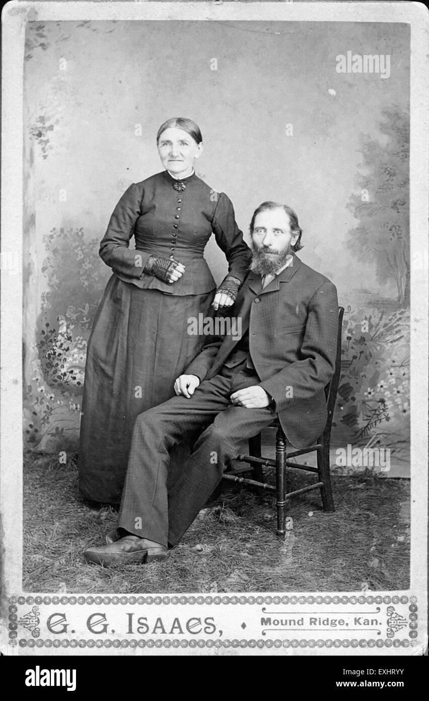 Questa fotografia cattura una coppia più anziana non identificata, probabilmente dell'inizio del XX secolo, mostrando l'abbigliamento e gli stili sociali del tempo. L'immagine offre uno sguardo sulla storia personale e sulle norme sociali del passato, presentando una rappresentazione senza tempo di una coppia nella vita successiva. Foto Stock