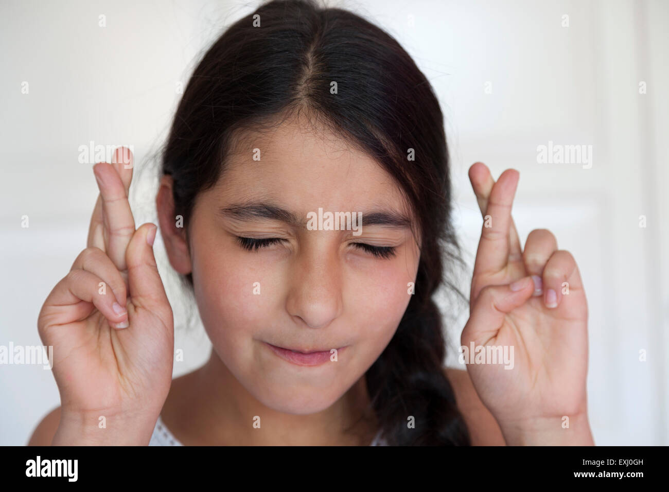 Ragazza adolescente incrocio le dita con gli occhi chiusi Foto Stock