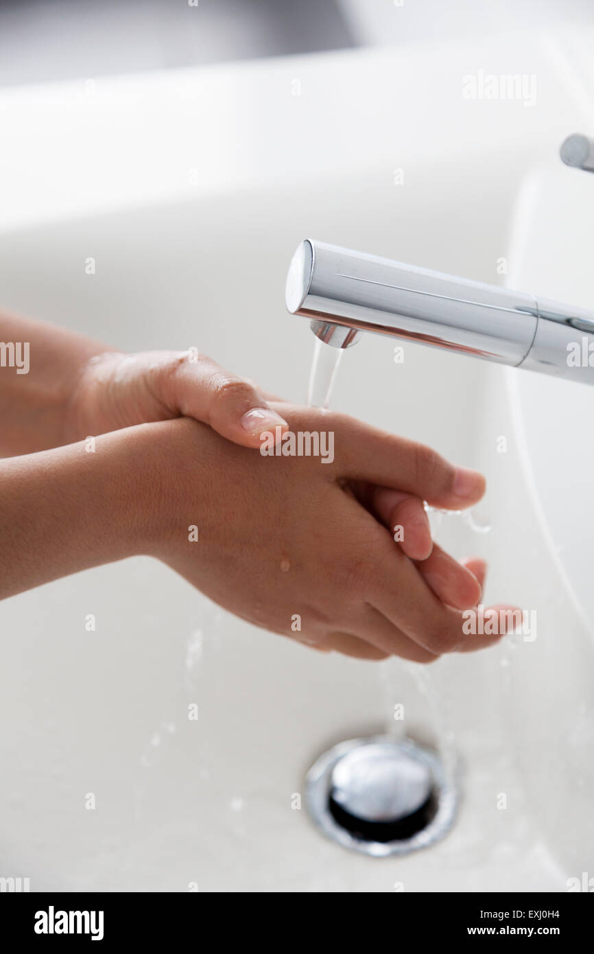Lavarsi le mani sotto il rubinetto di acqua Foto Stock