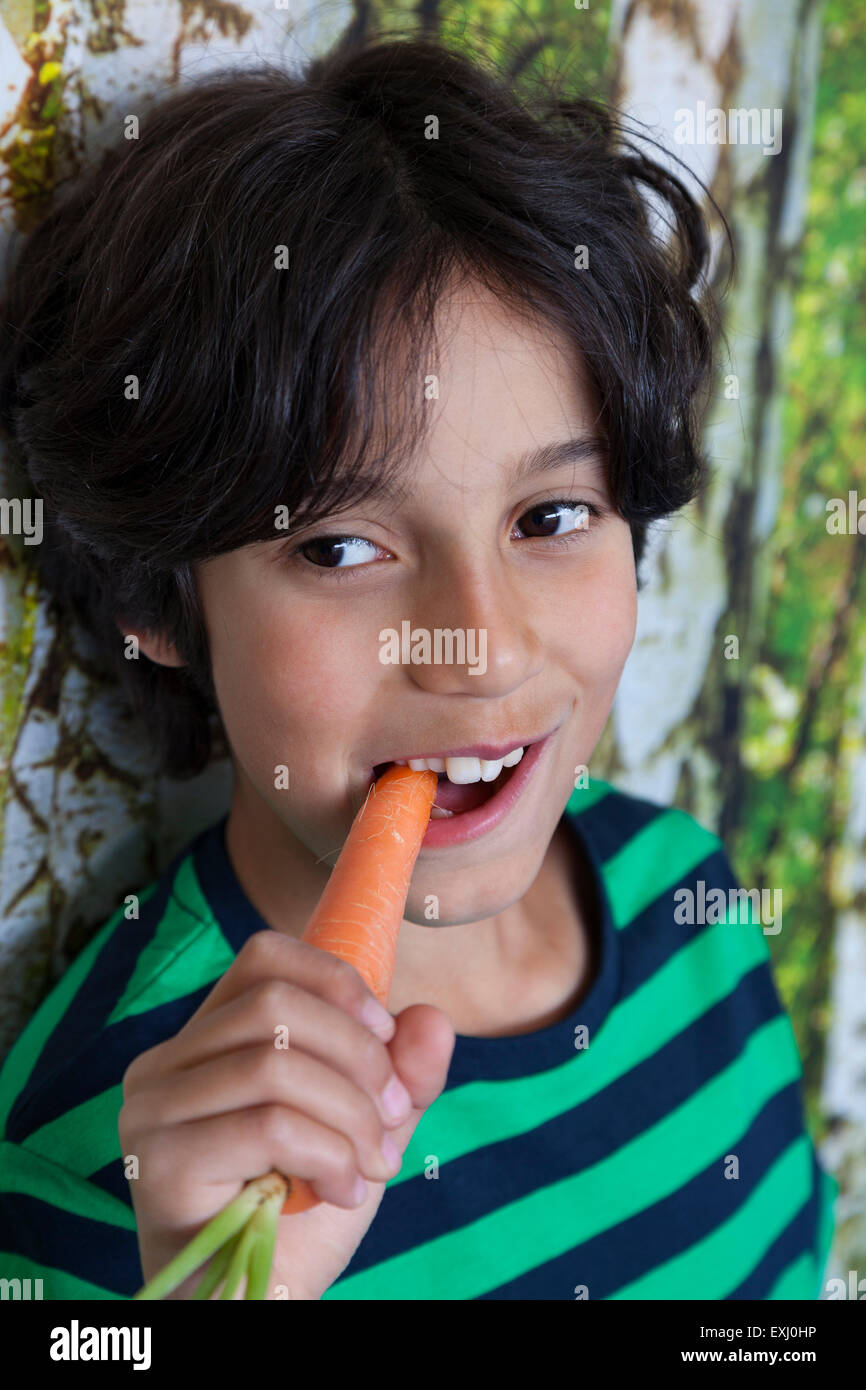 Ragazzo adolescente a mangiare una carota fresca Foto Stock