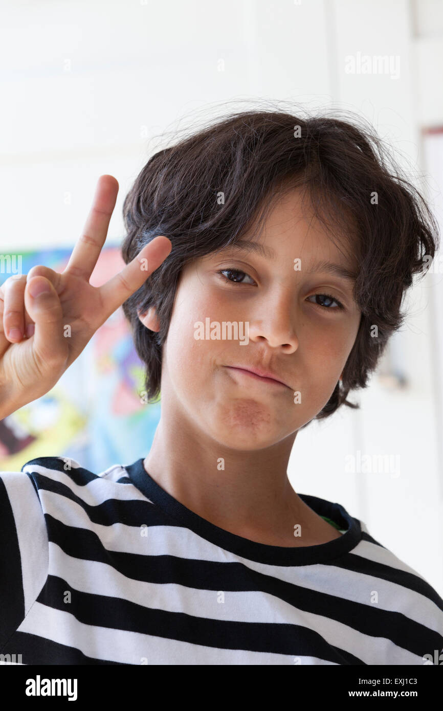 Dieci anni di vecchio ragazzo facendo un segno V withhis dita, Foto Stock