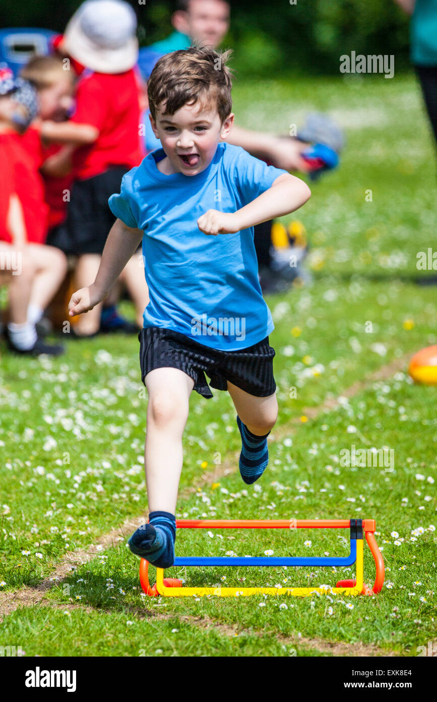 Giovane ragazzo saltando un ostacolo in un pre-scuola di sport giorni di gara Foto Stock
