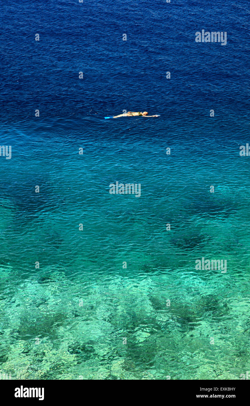 Lonely donna nuoto dorso ai Asteria spiaggia, 'Vaporia' quartiere, Ermoupolis, Syros Island, Cicladi, Egeo, Grecia. Foto Stock