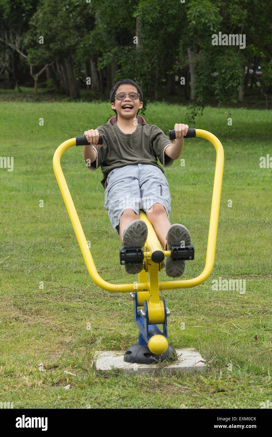 Asian Thai teen boy sorridente esercitando sulle attrezzature sportive in giardino Foto Stock