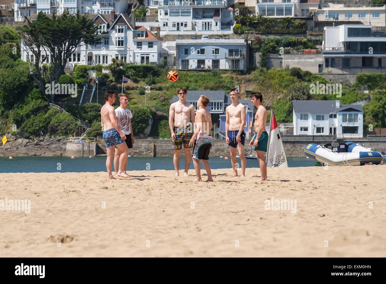 Mill Bay Beach, Saltcombe, Devon, Regno Unito. Gruppo di adolescenti gli uomini a giocare a calcio sulla spiaggia in estate Foto Stock