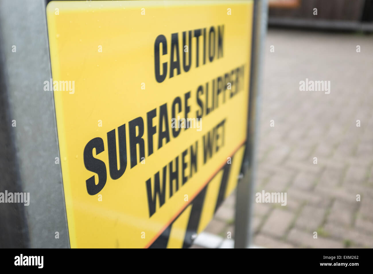 Attenzione superficie scivoloso quando è bagnato, cartello giallo Foto Stock