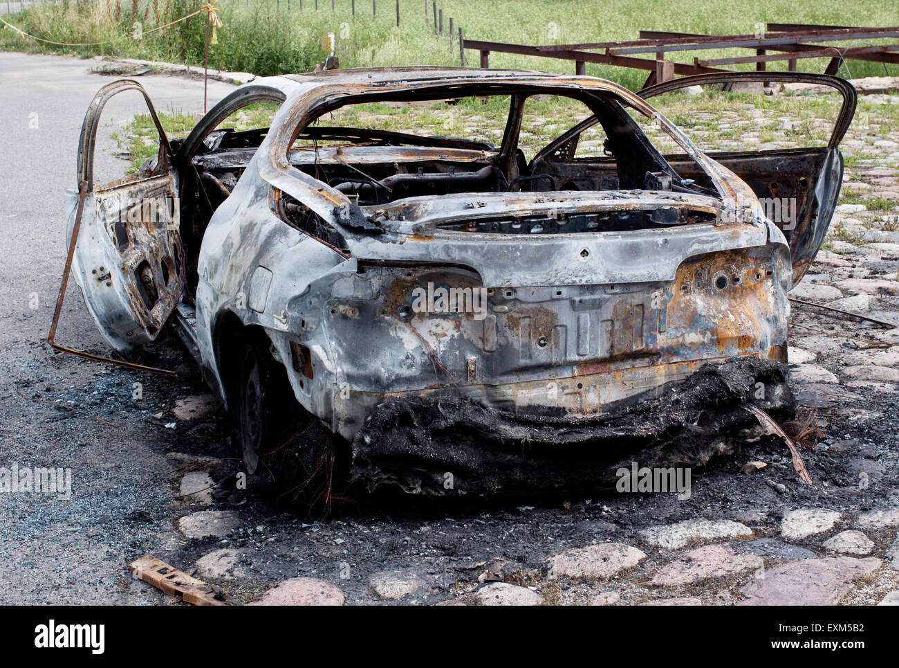 Bruciata arrugginita vecchia auto vicino alla strada Foto Stock
