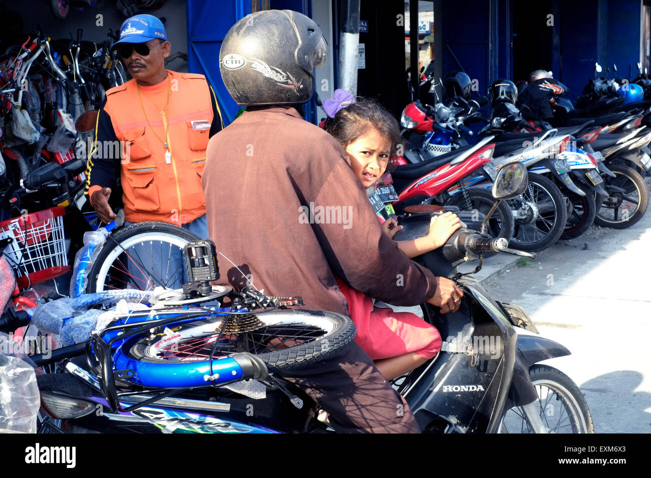 Giovane ragazza locale sat con suo padre sul ciclo del motore con la sua nuova bicicletta legata sul retro in solo java indonesia Foto Stock