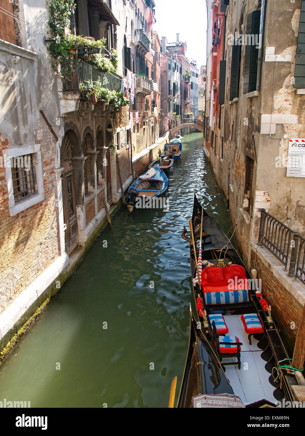 Vista di una gondola ormeggiata in uno stretto canale nella città di Venezia con belle case sui lati. Venezia. L'Italia. Foto Stock