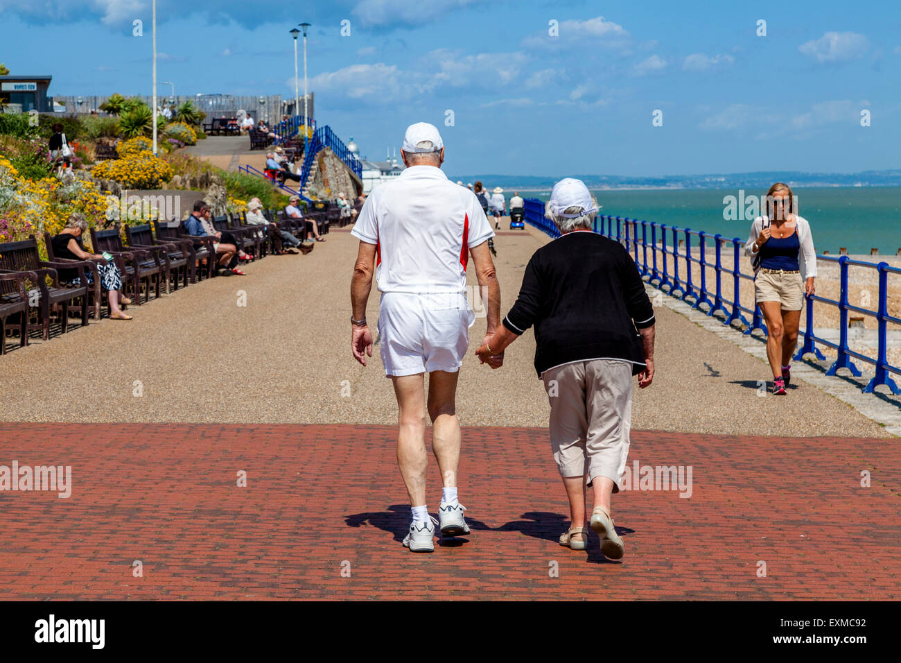 Una coppia di anziani camminare lungo la passeggiata a mare, Eastbourne, Sussex, Regno Unito Foto Stock