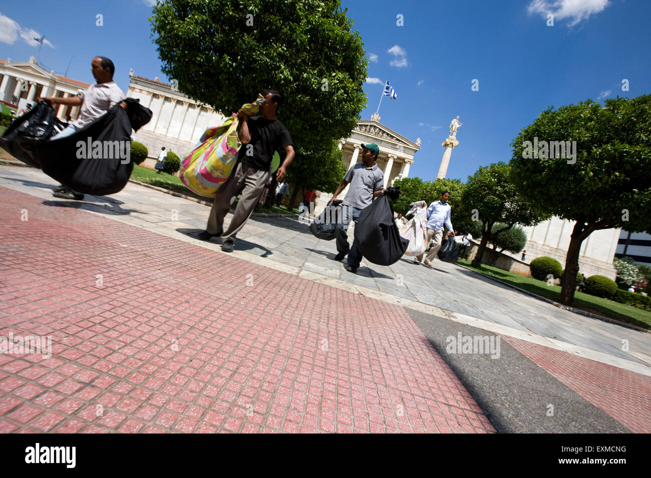 Lavoratori migranti venditori ambulanti in esecuzione con i loro beni per sfuggire dalla polizia li insegue all Università di Atene, Panepistimiou street. Foto Stock