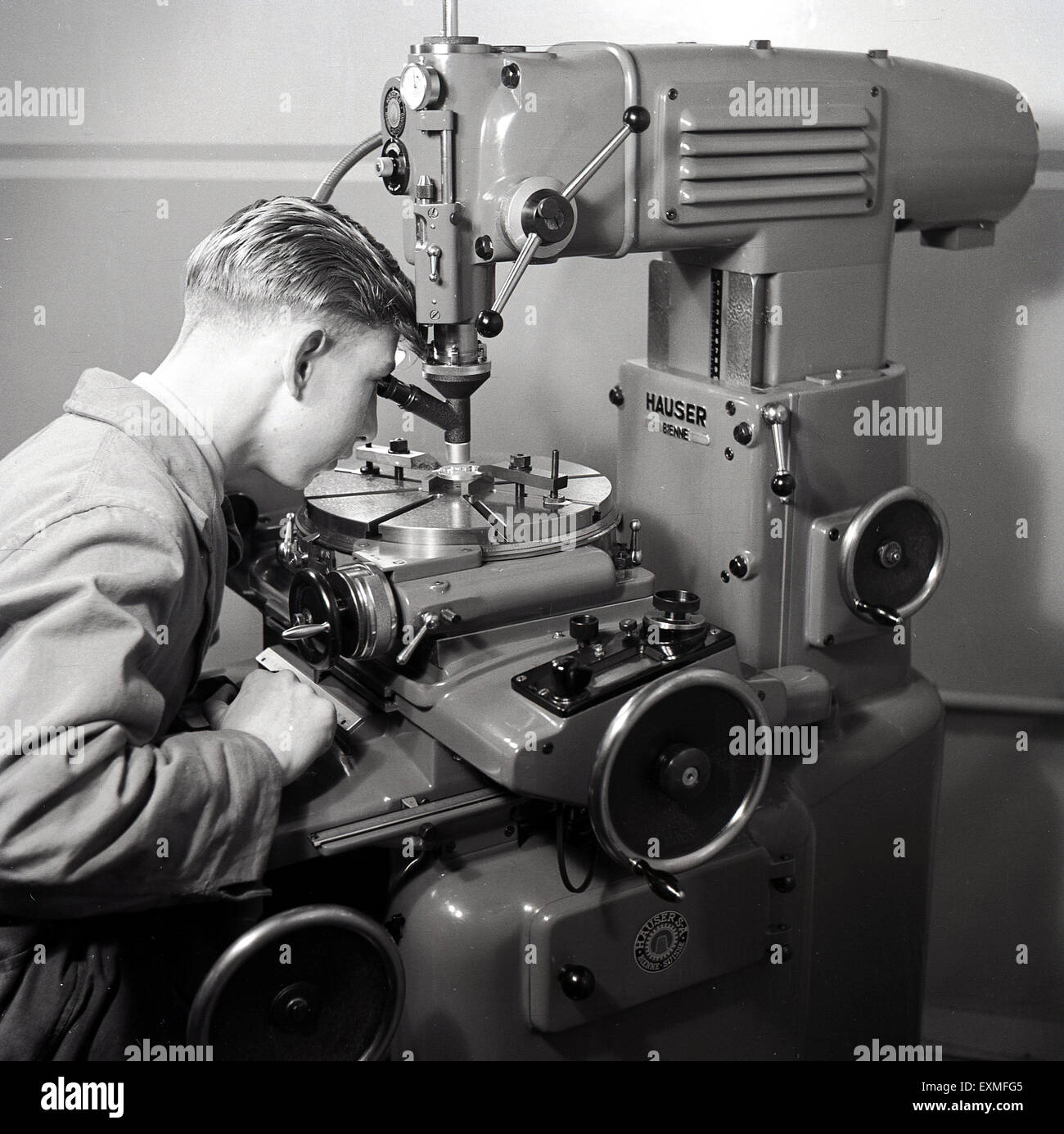 anni '50, immagine storica che mostra un giovane apprendista maschile che utilizza una macchina utensile di precisione in metallo azionata da una potenza soppressa. Una macchina utensile è un utensile, ad azionamento elettrico o manuale per la lavorazione del metallo mediante taglio, molatura o sagomatura. Foto Stock