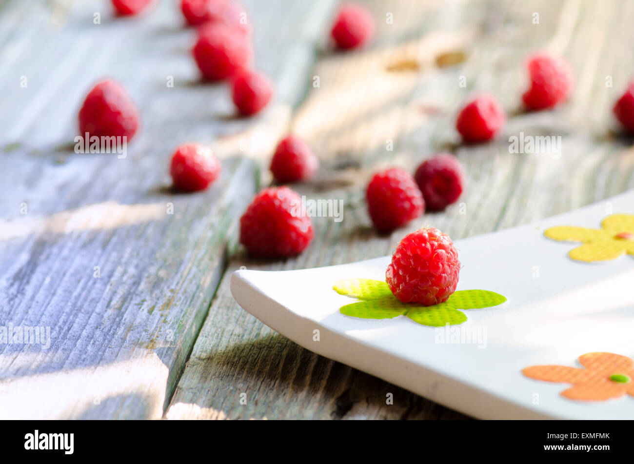 Rasberries sulle moderne piastra bianca isolata su uno sfondo di legno Foto Stock