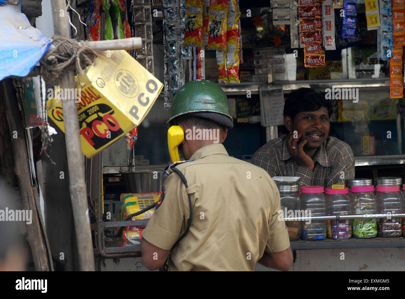 Una polizia constable fa una telefonata locale da un negozio a Bombay ora Mumbai ; Maharashtra ; India Foto Stock