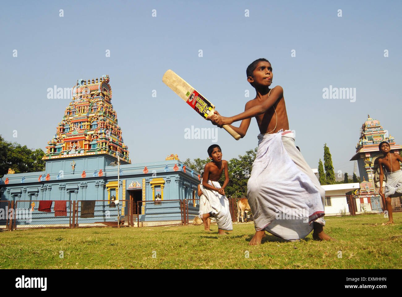 Ragazzi indossando lungis bianco gioco di cricket nella parte anteriore del tempio a Navi Mumbai , Nuova Bombay , Maharashtra , India Foto Stock