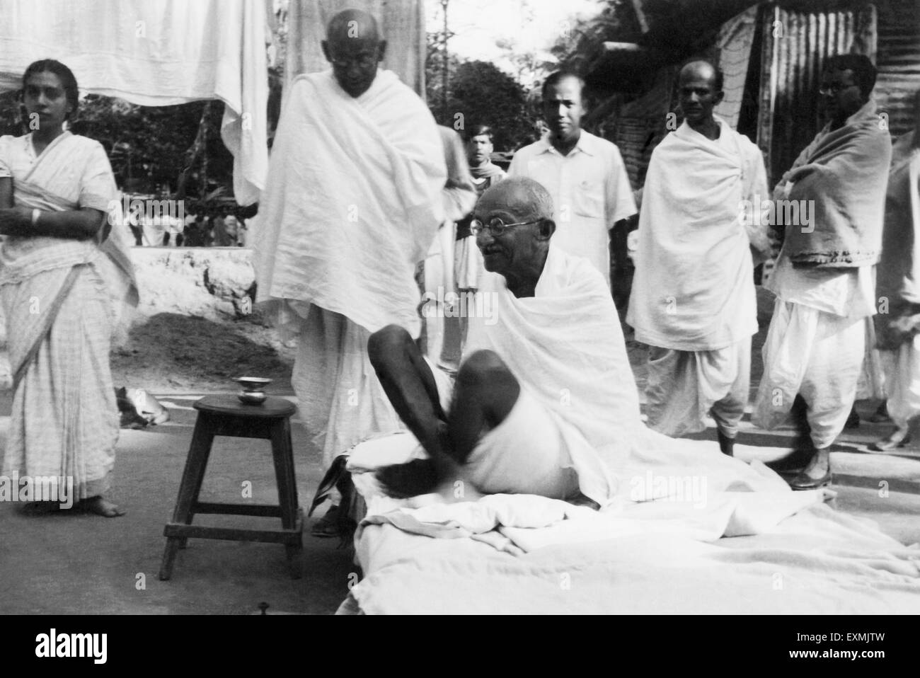 Il Mahatma Gandhi seduto su un letto in Noakhali Bengala Orientale ; Novembre 1946 Sushila Nayar Satish Das Gupta Foto Stock