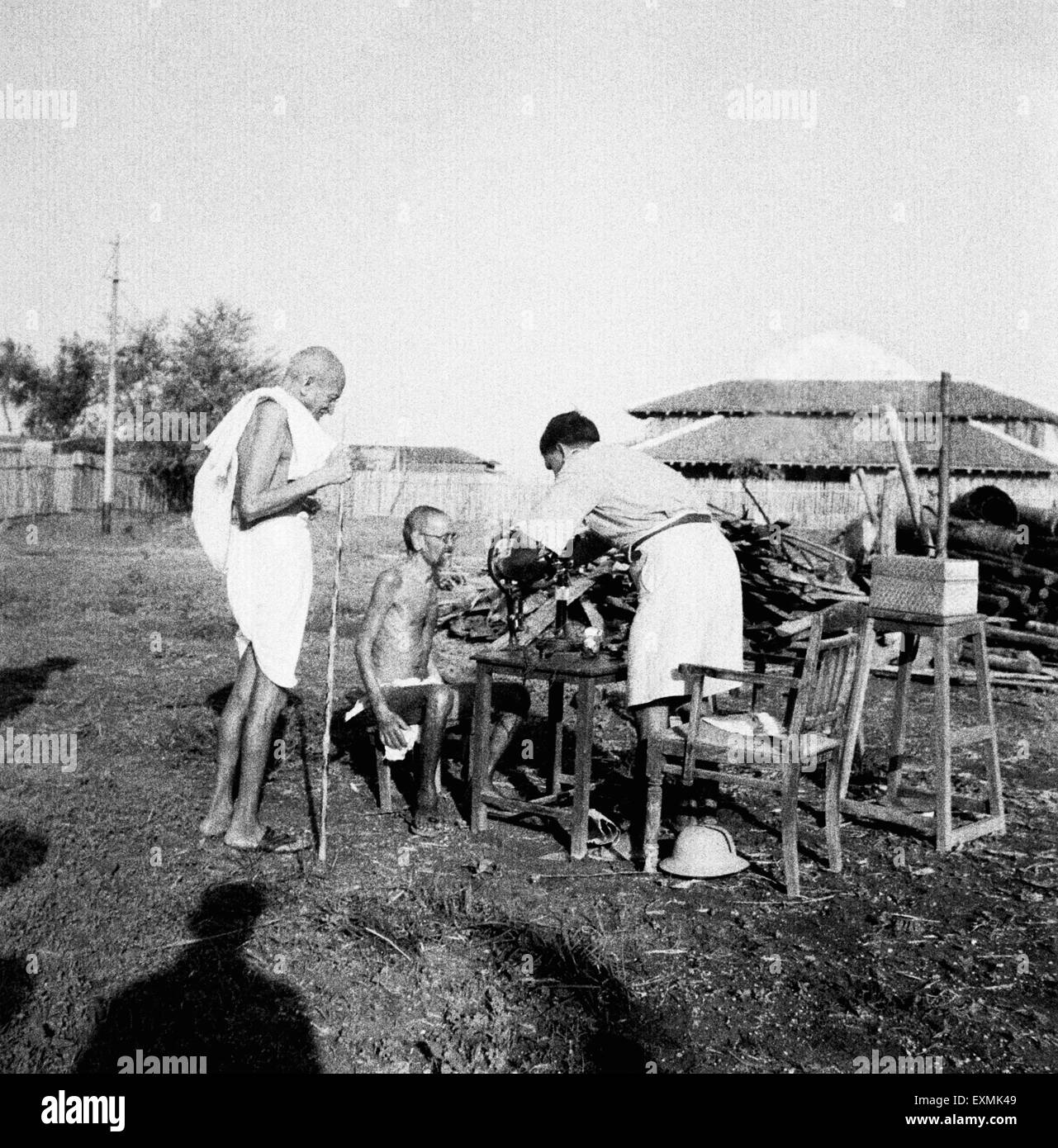 Il Mahatma Gandhi osservando lebbroso Parchure paziente Shastri esaminata dall'esterno da parte di un medico Sevagram Ashram Foto Stock