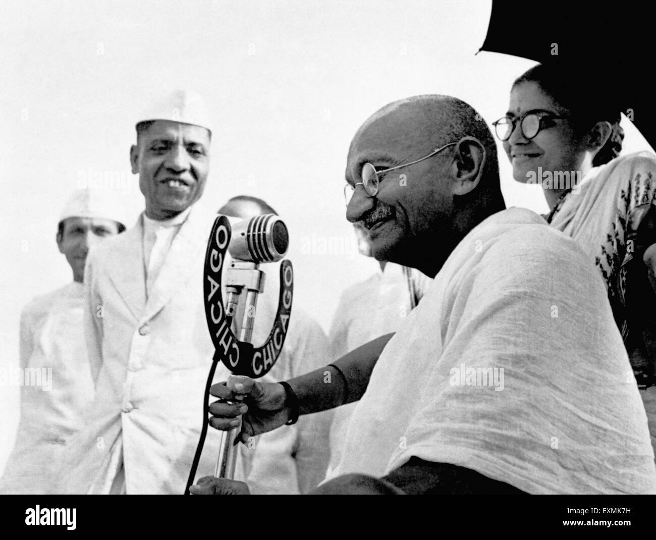 Il Mahatma Gandhi parlando in un microfono a Pune 1944 Abha Gandhi dietro Foto Stock