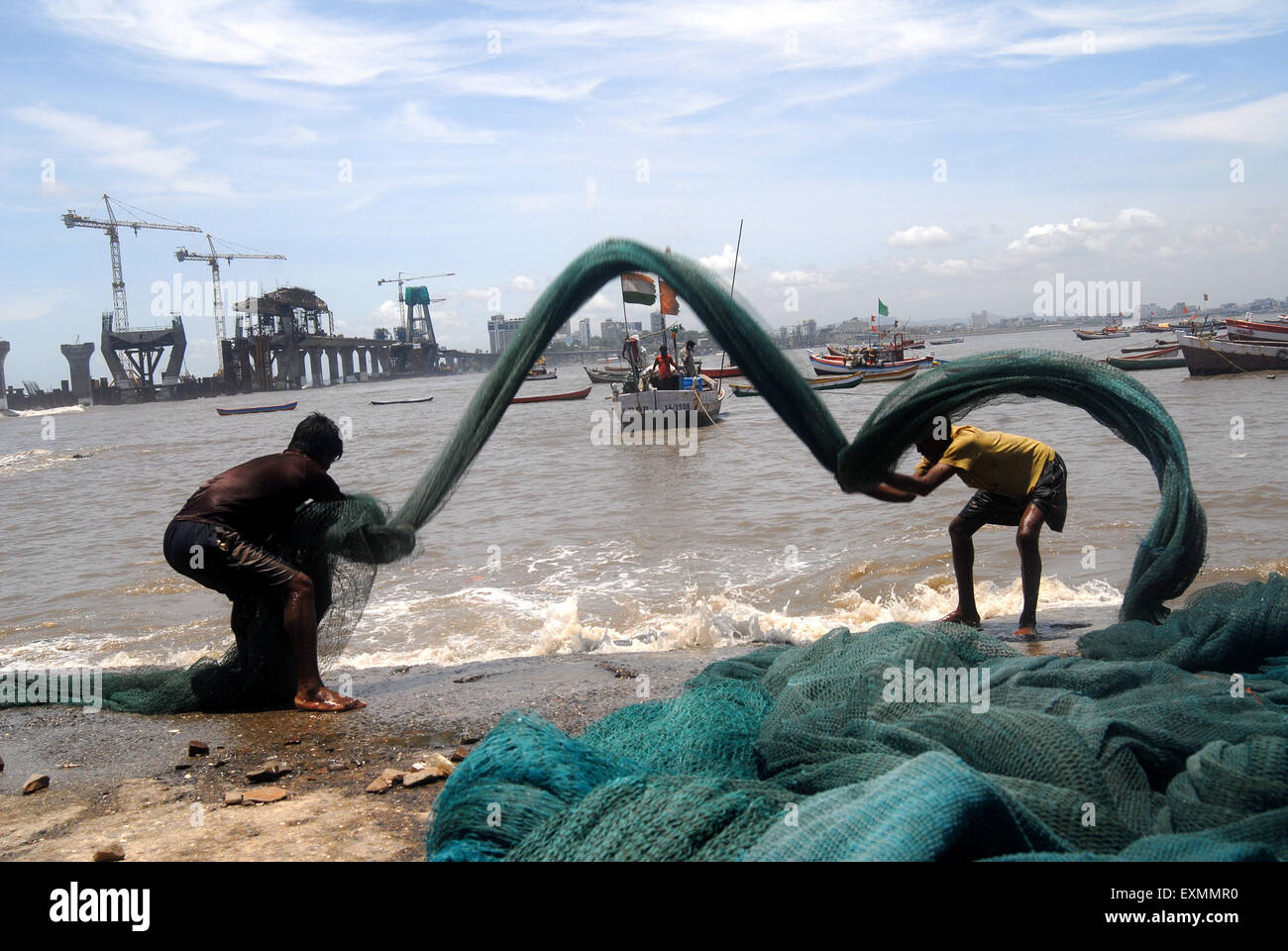 I pescatori pulire le loro reti da pesca nel contesto di Bandra Worli Sea Link a Worli villaggio in Mumbai Bombay Foto Stock