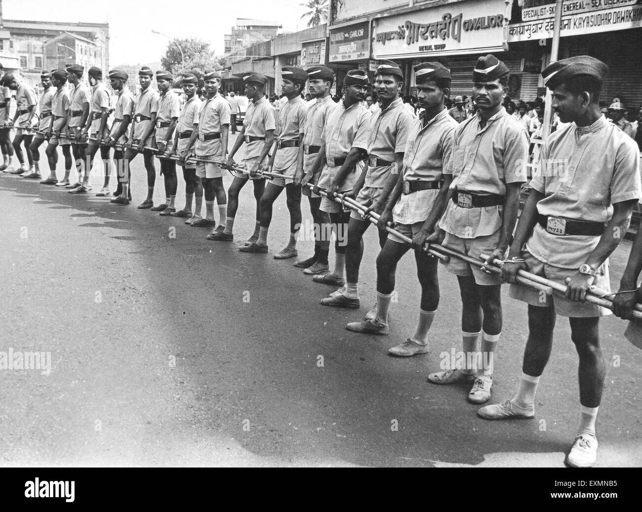 La polizia poliziotti in piedi mano nella mano in una riga tenendo manganelli Bombay Mumbai India Maharashtra Foto Stock