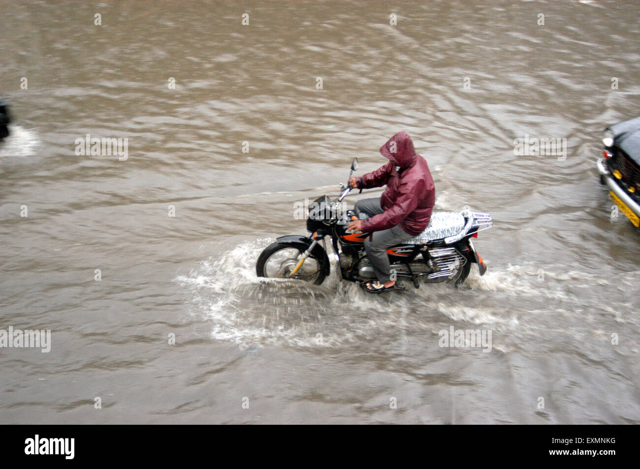 Biker moto impermeabile rider riding monsone di acqua di pioggia strade allagate Vidyavihar Bombay Mumbai India Foto Stock