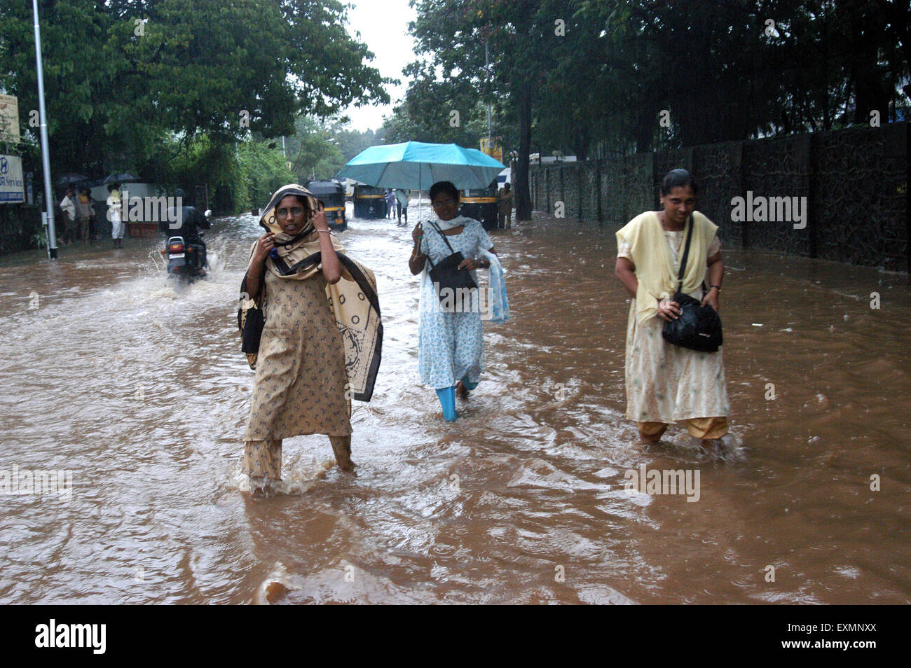 Tre women rainfall camminando monsone allagato street acqua Vidyavihar Mumbai India Maharashtra Foto Stock