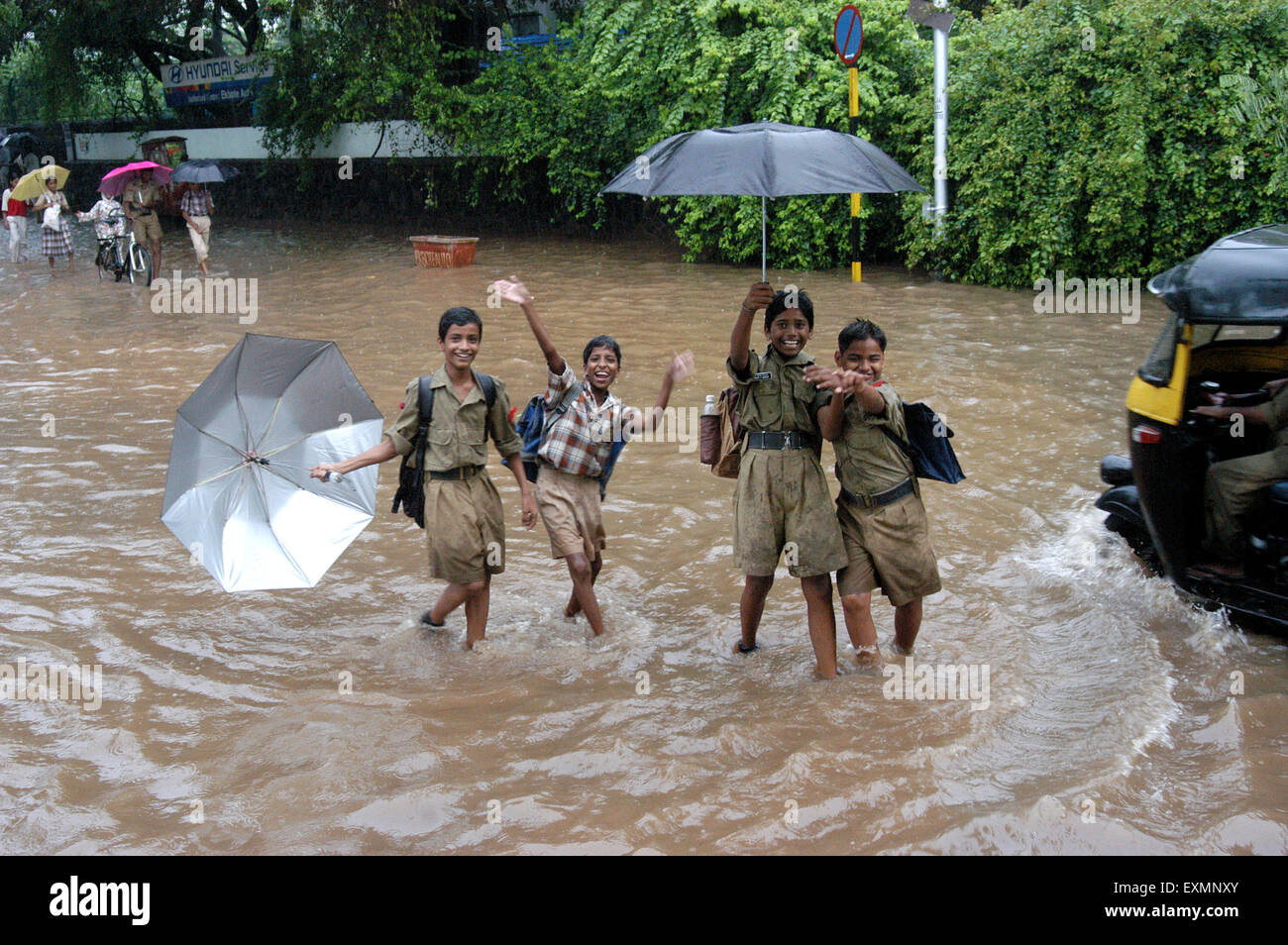Four school boys godendo di piogge monsoniche in pioggia strade allagate in Vidyavihar Mumbai India Maharashtra Foto Stock