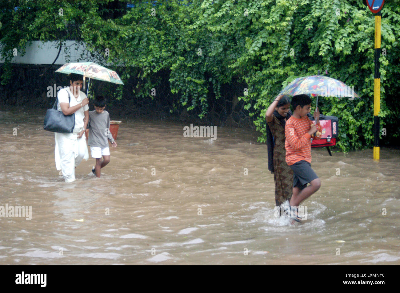 Persone women bambini passeggiate ombrello flooded street acqua monsone rainfall Vidyavihar Bombay Mumbai India Maharashtra Foto Stock
