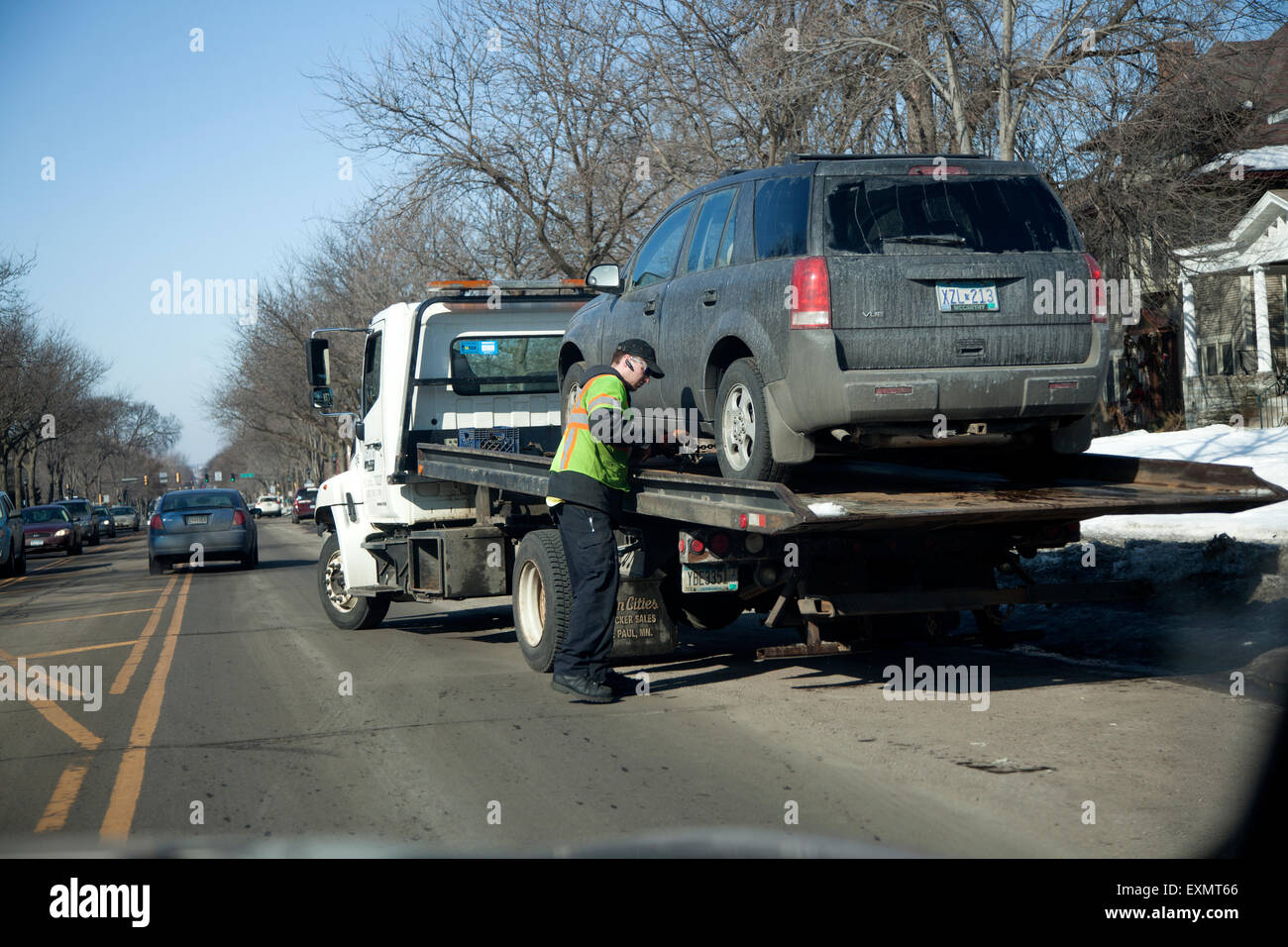 Trainare il carrello operatore automatico di fissaggio per probabile ride a confiscare lot per illegale parcheggio d'inverno. St Paul Minnesota MN USA Foto Stock
