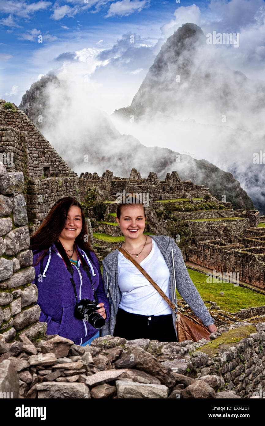 Due giovani viaggiatori femmina in posa con il Machu Picchu in background. Foto Stock