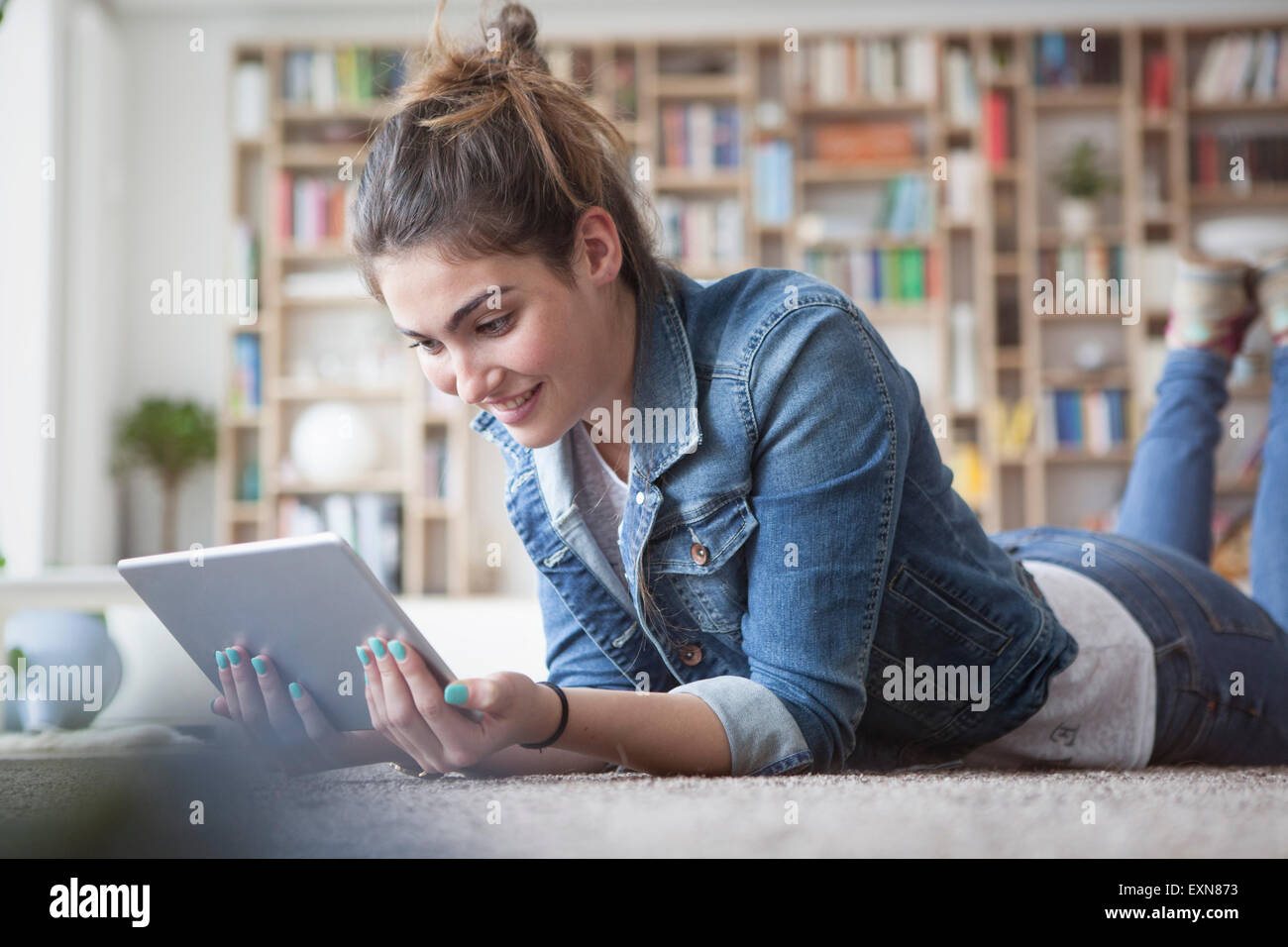 Giovane donna con tavoletta digitale in casa Foto Stock