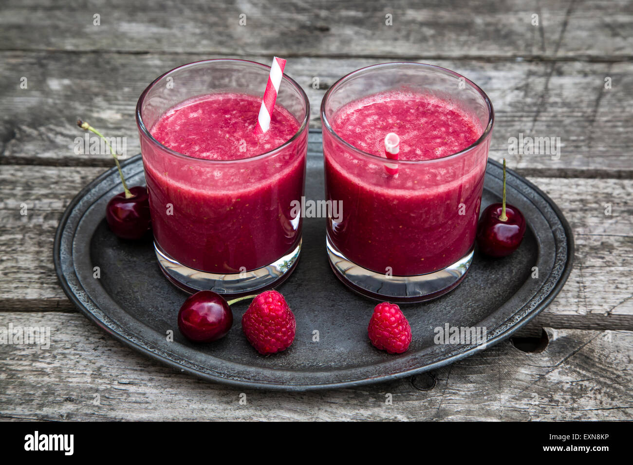 Frullato di rosso in bicchieri, lampone, ciliegia su legno Foto Stock