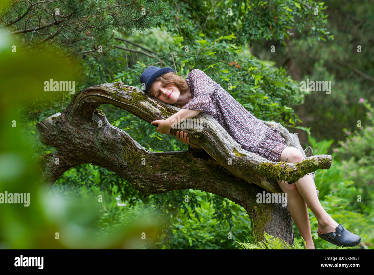 Felice giovane donna sdraiata su un tronco di albero Foto Stock