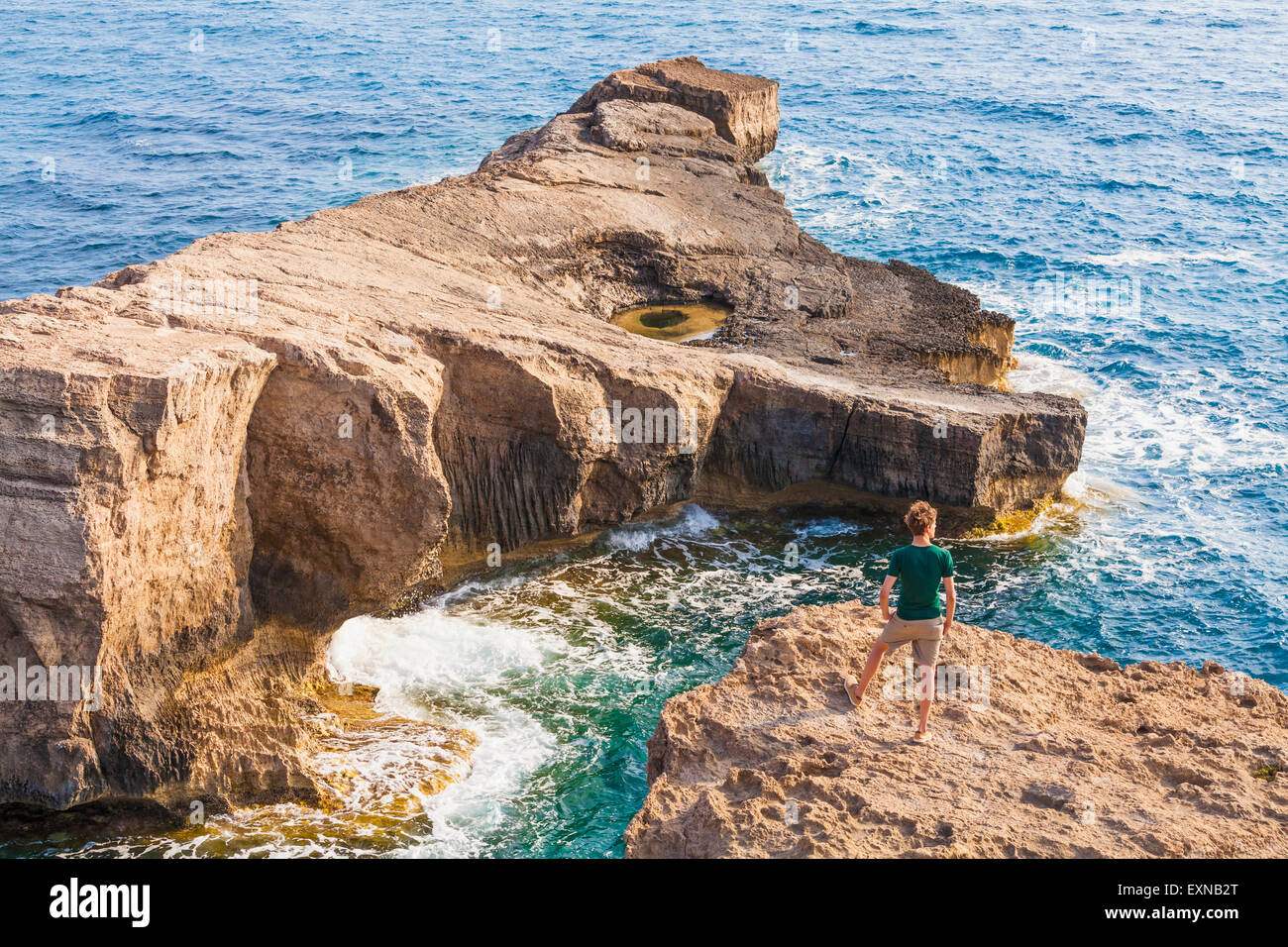 Grecia Isole dell' Egeo, Rodi, giovane uomo in piedi sull'isola rocciosa Foto Stock