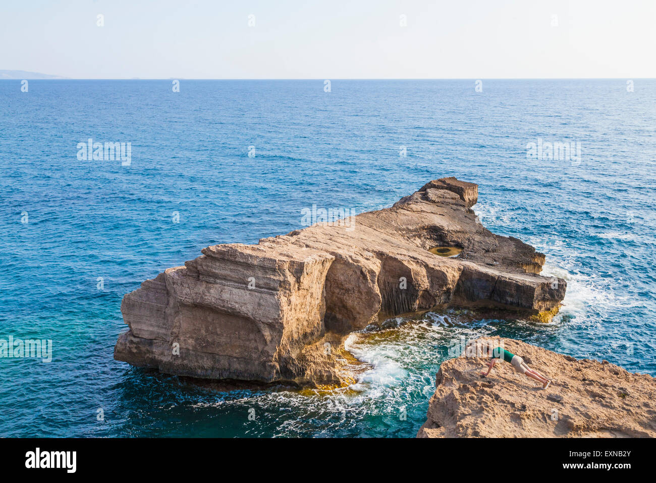 Grecia Isole dell' Egeo, Rodi, giovane uomo che fa pushups sulla costa rocciosa Foto Stock