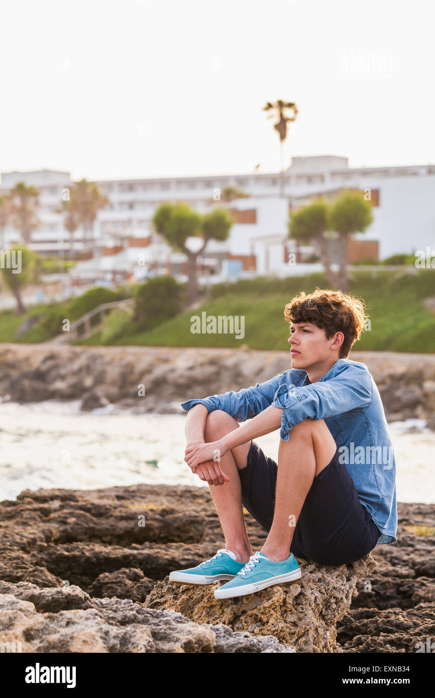 La Grecia, Rodi, giovane uomo seduto sul lungomare guardando a distanza Foto Stock