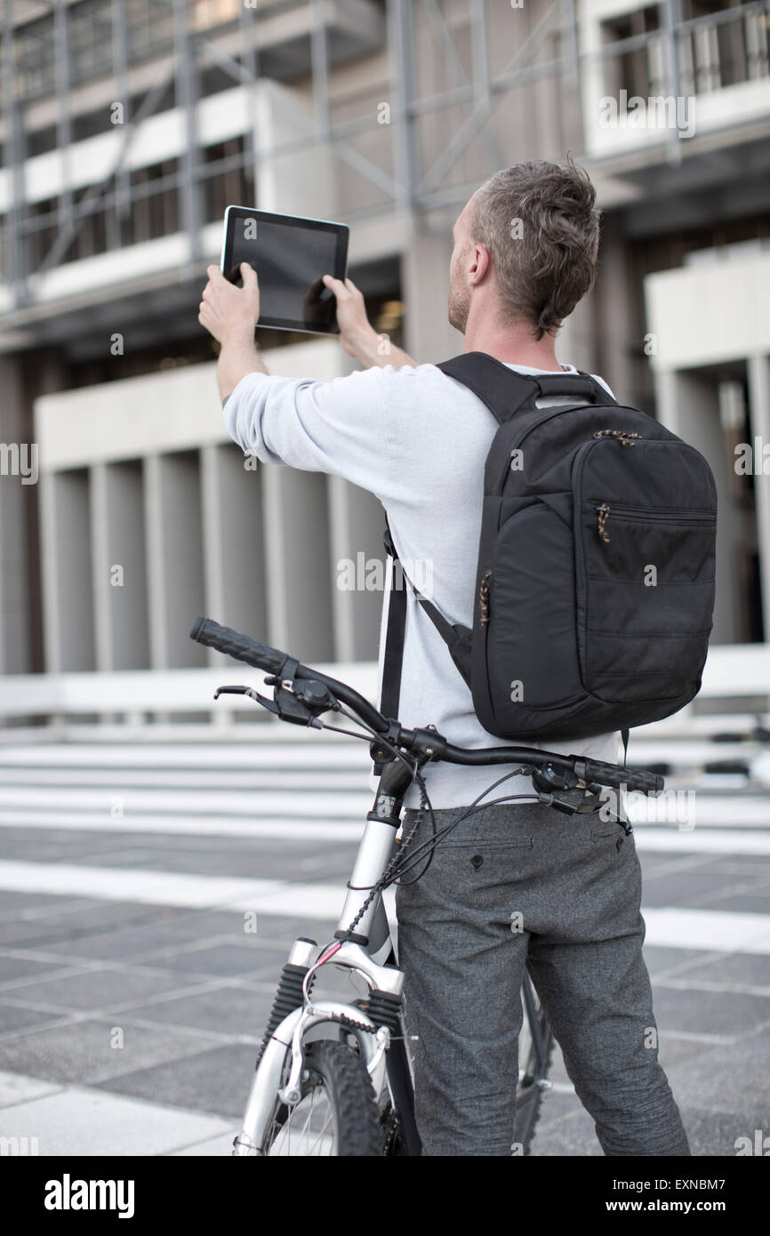 Uomo con zaino in spalla e la moto di scattare una foto con la tavoletta  digitale Foto stock - Alamy