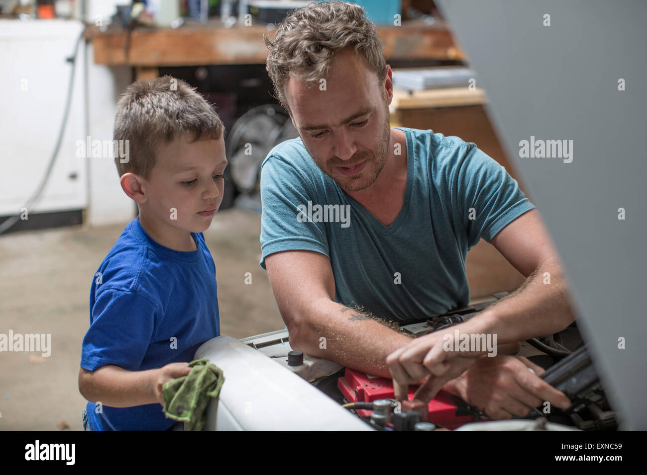 Figlio aiutando il padre nel garage di casa a lavorare sulla vettura Foto Stock