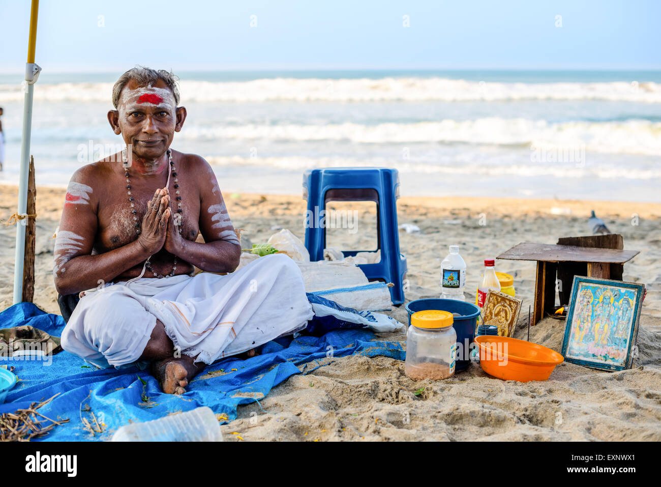 Varkala, India - 22 Febbraio 2013: bramino indù con attributi religiosi si siede in Namaste mudra sulla spiaggia. Varkala Beach, K Foto Stock
