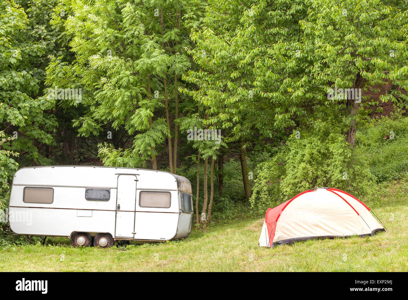 Vecchio camping rimorchio e tenda nella foresta. Foto Stock